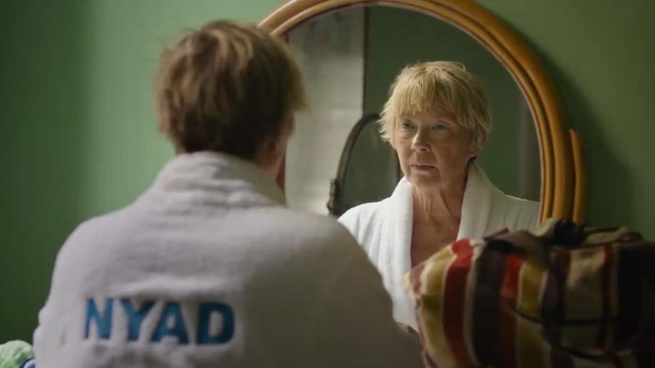 Annette Bening as Diana Nyad, looking at her reflection in a mirror in the Netflix film Nyad.