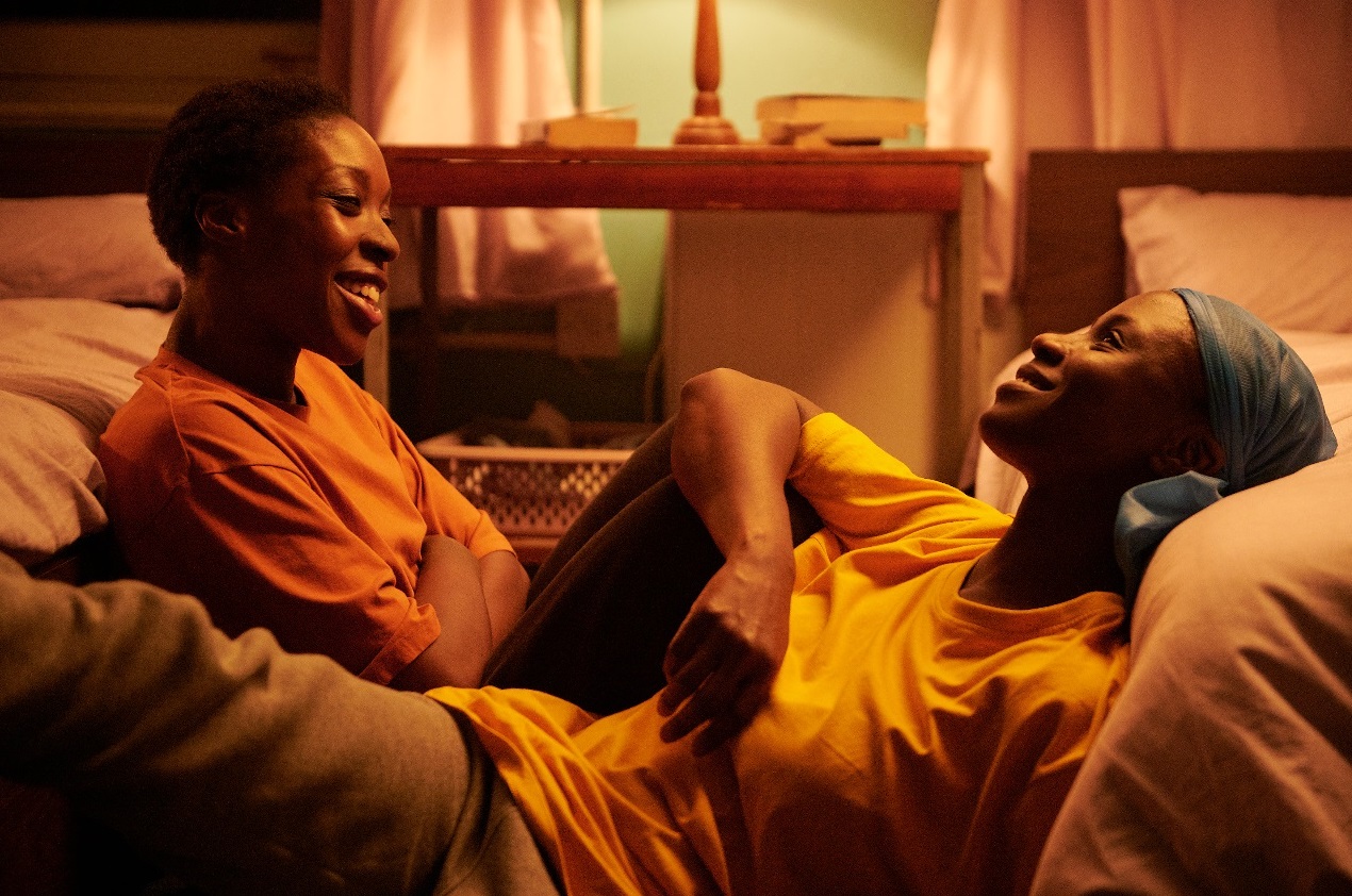 Isio (Ronke Adekoluejo) and Farah (Ann Akinjirin) sit between their two beds and chat in Dreamers.