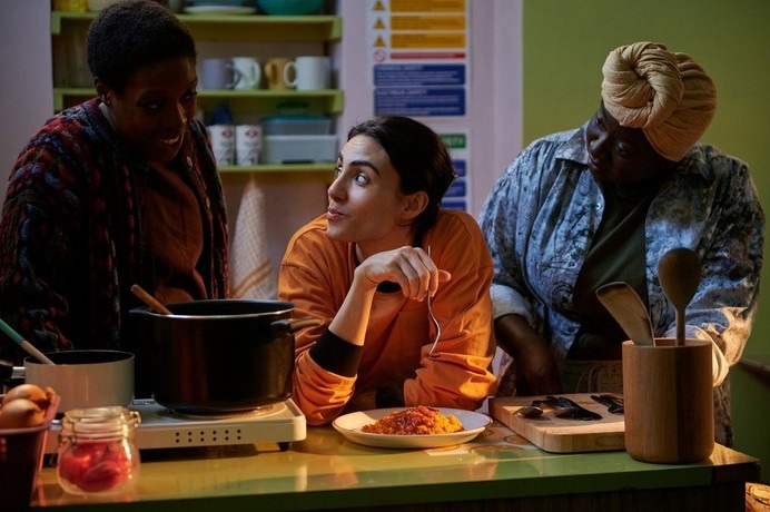 Atefah (Aiysha Hart) tests a dish of food while Isio (Ronke Adekoluejo) and Nana (Diana Yekinni) look on in Dreamers