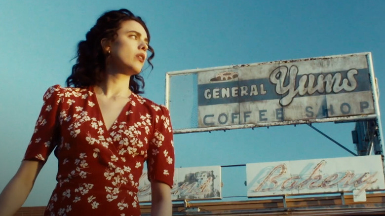 Honey (Margaret Qualley) walks in front of a billboard in Honey Don't