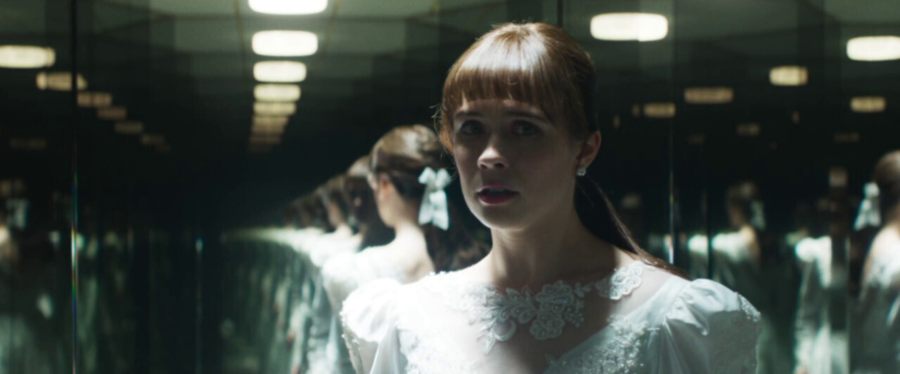 Judy Warren (Mia Tomlinson) in a wedding dress looking scared in a hall of mirrors in The Conjuring: Last Rites