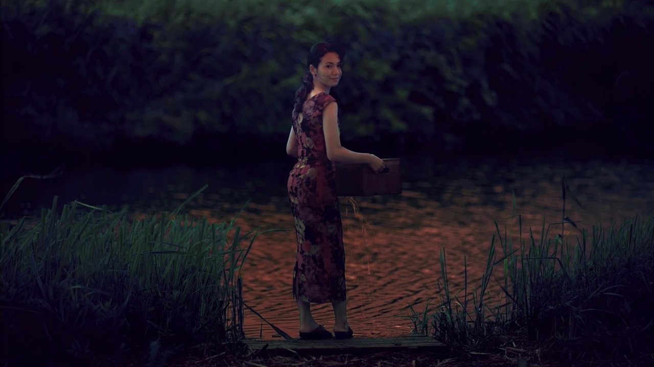 Sachiko (Fumi Nikaidô) holds a box by the river in A Pale View of Hills