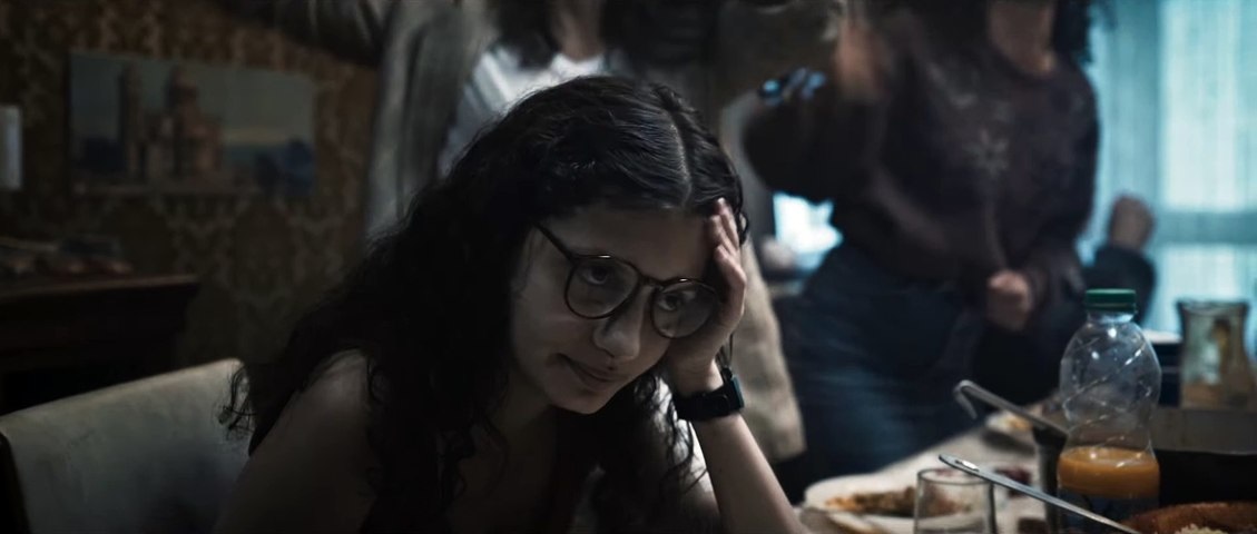 Mélissa Boros with head in hand at a dinner table in Alpha.