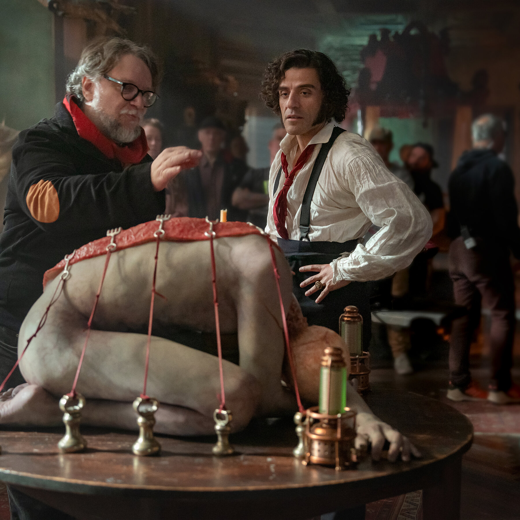Guillermo del Toro directing Oscar Isaac in a scene with a bound up crouching cadaver in Frankenstein. 