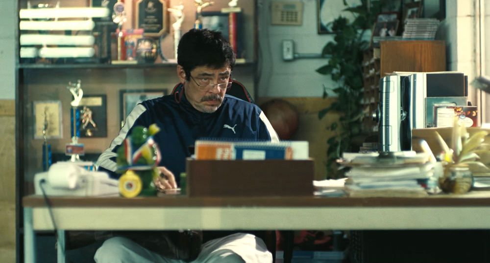 Sensei Sergio St. Carlos (Benicio Del Toro) sat at his office desk in One Battle After Another