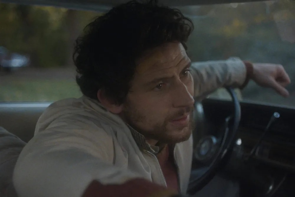 James Blaine Mooney (Josh O'Connor) sitting in a car in The Mastermind