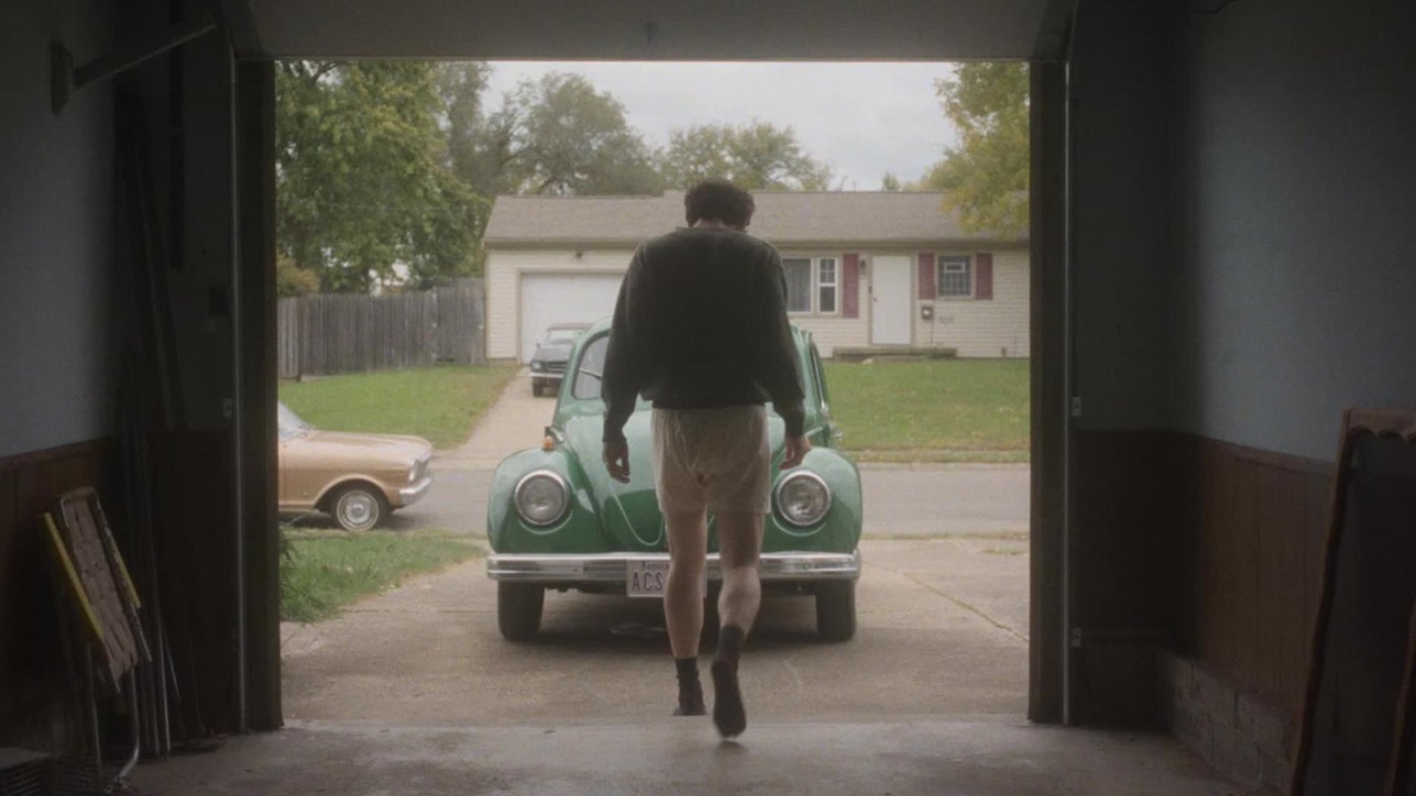 James Blaine Mooney (Josh O'Connor) walks out of his garage door in baggy white boxer shorts in The Mastermind