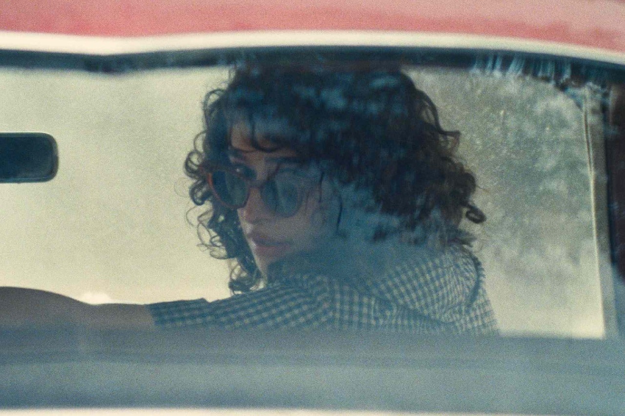 Rachel (Odessa A'zion) looks out of the back window of a car in Marty Supreme