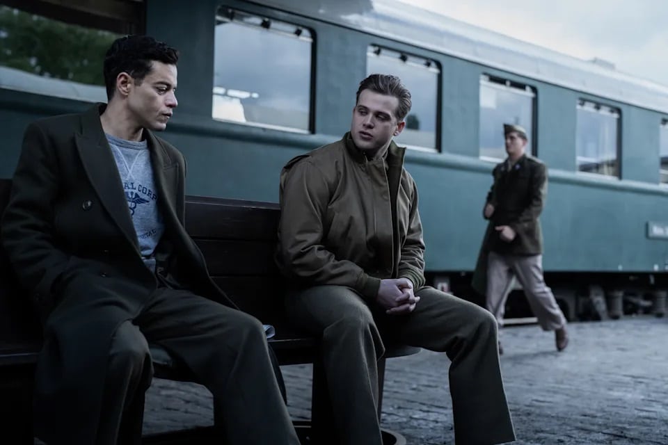Douglas Kelley (Rami Malek) sat on a station platform next to Howie Triest (Leo Woodhall) in Nuremberg.