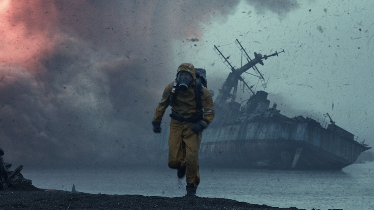Gerard Butler as John Garrity running in a Hazmat suit with a wrecked ship behind him in Greenland 2: Migration.