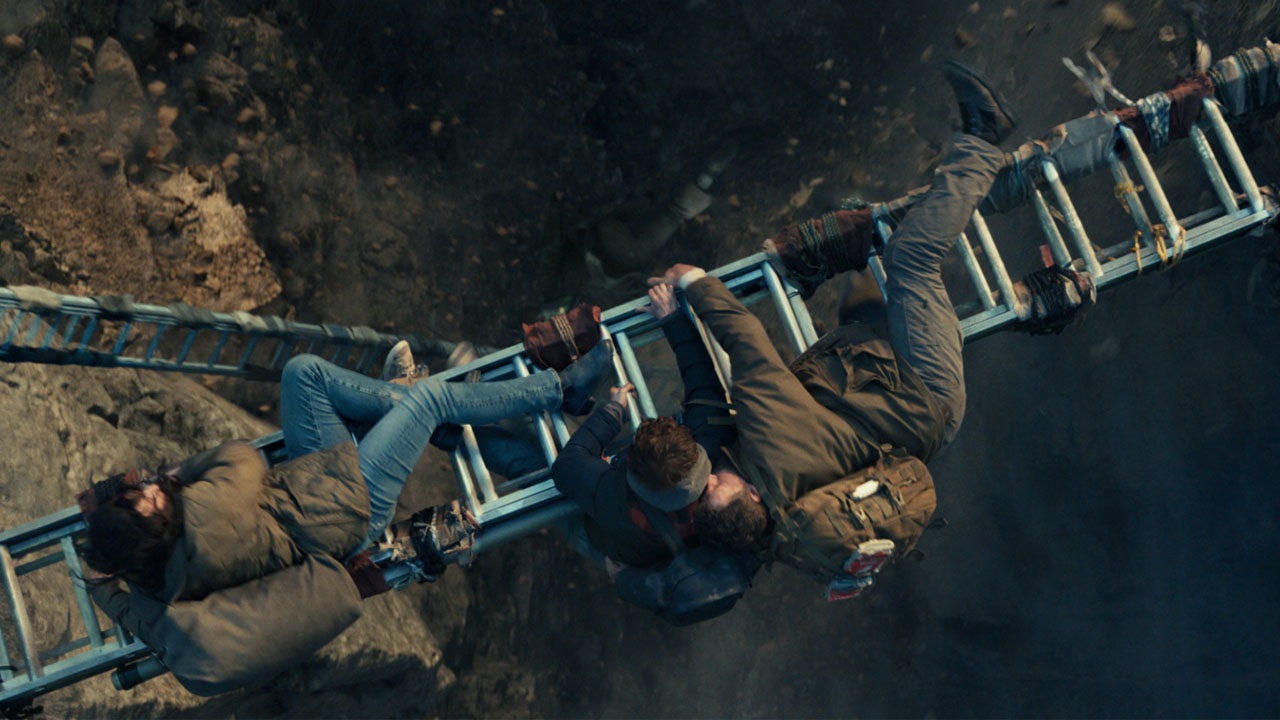 The Garrity family crossing a chasm via a ladder in Greenland 2: Migration.