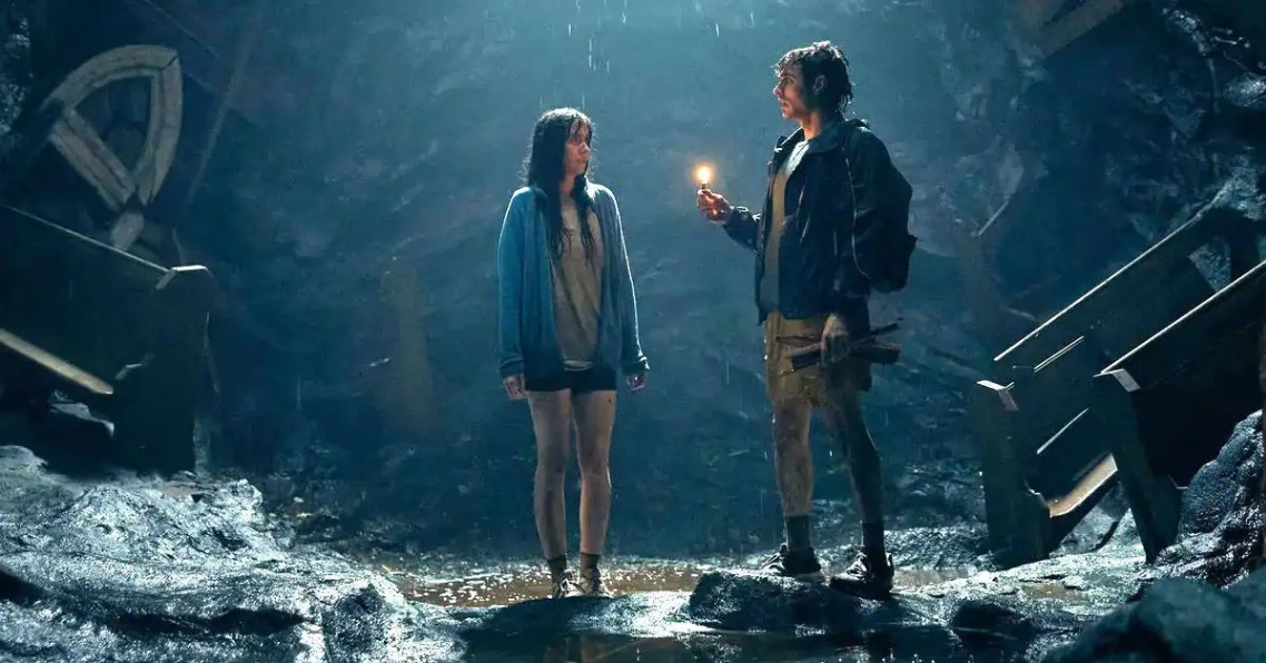 Millie and Tim stand shivering in an underground cave in the horror film "Together".