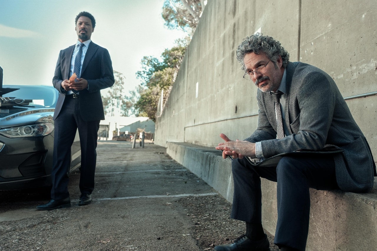 Lou (Mark Ruffalo) sits on a wall with his partner Tillman (Corey Hawkins) standing nearby in Crime 101.