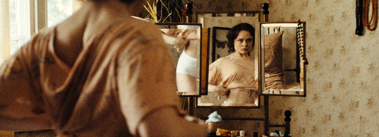 A woman examines her body in a mirror in Sound of Falling.