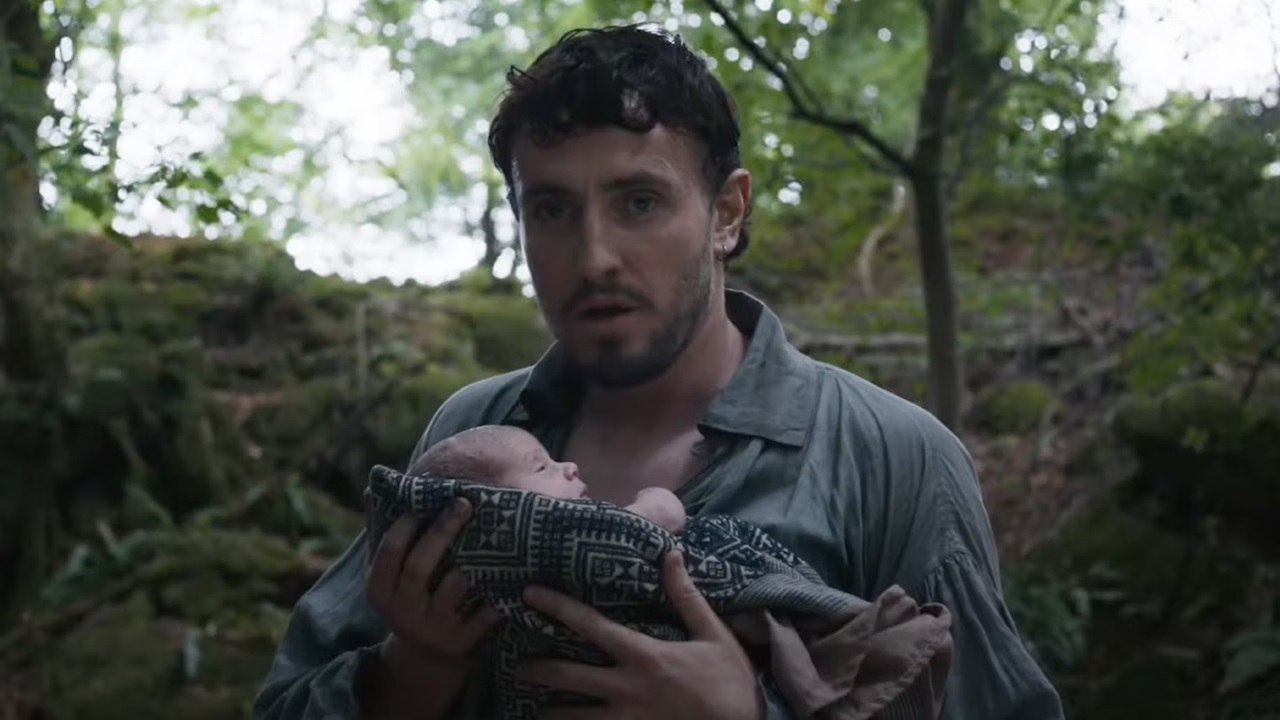 Paul Mescal holding his child in the woods in the film Hamnet.