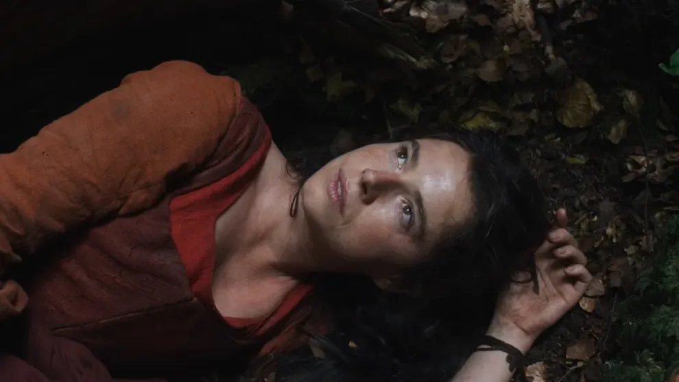 Jessie Buckley as Agnes lying in the woods in the film Hamnet.
